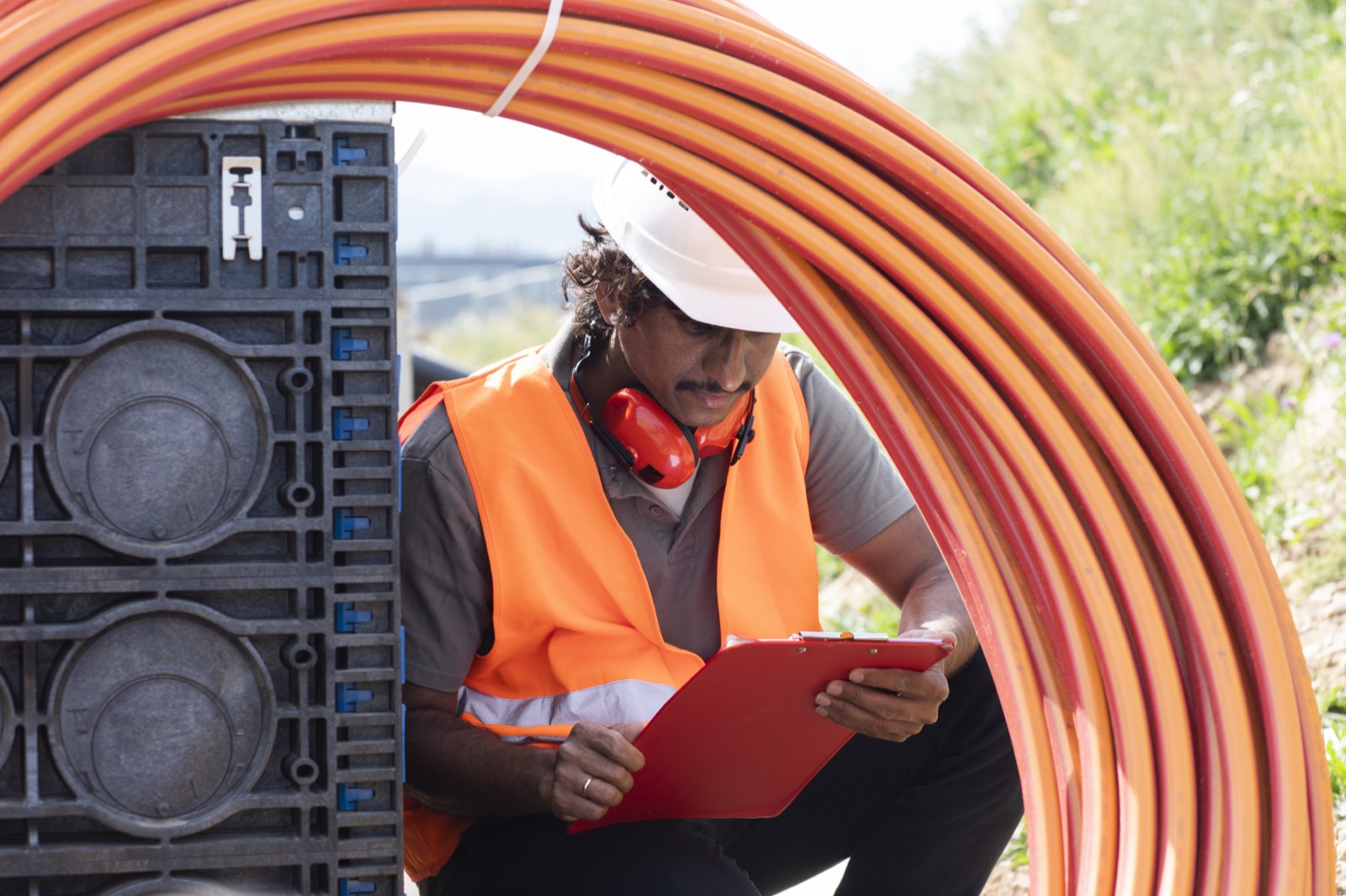 Worker documenting fiber conduit installation on a clipboard