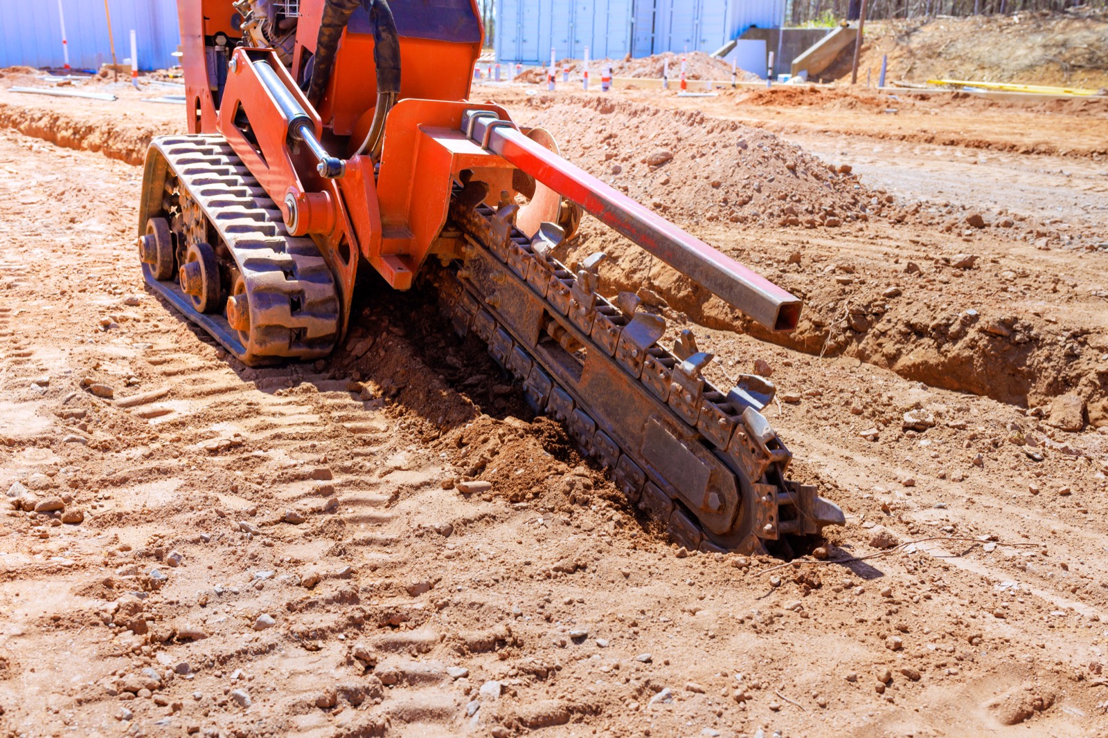 Trencher cutting a furrow for fiber conduit